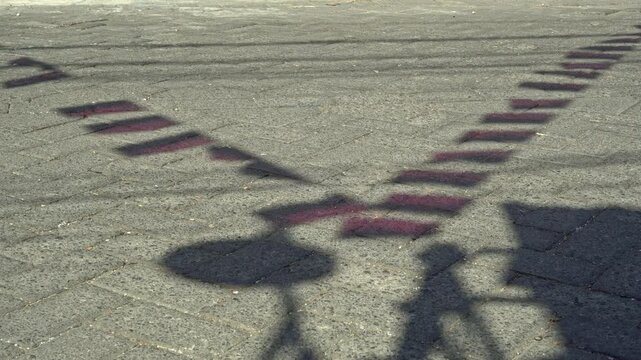 Captivating shadows of festive national pennants cast on an outdoor paved stone ground surface under bright sun, creating a unique abstract texture pattern.