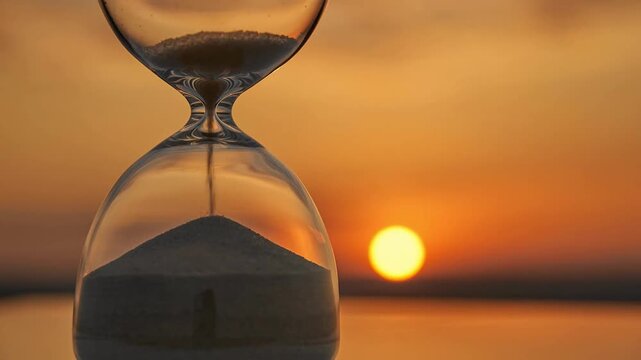 Hourglass with flowing sand sunset sunrise, symbol time passing, reflection on life, warm golden light, silhouette glass against horizon, patience, countdown, eternity endings. time lapse. glass hour