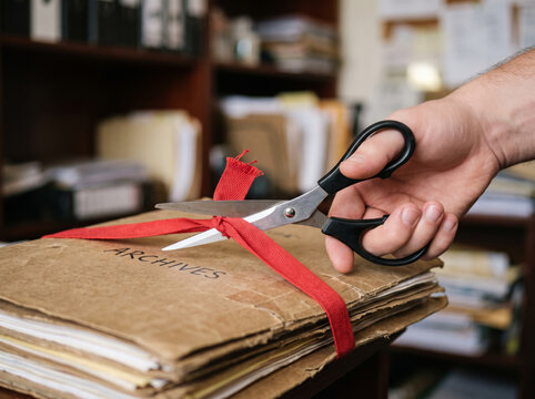 Cutting Red Tape Ribbon with Scissors over Archive Document Files Folder