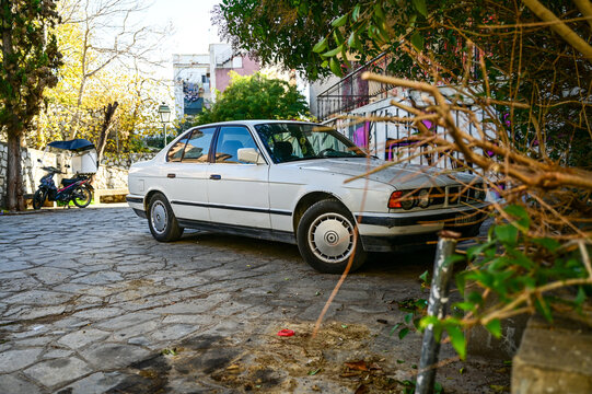 White BMW 5 Series sedan (E34 generation)&mdash;a car from the 1980s and 1990s&mdash;parked in a paved square in Thessaloniki; a classic German "youngtimer," Greece 04.112.2025
