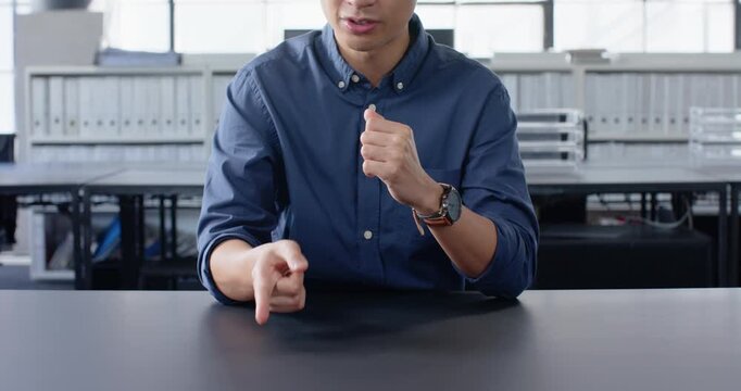 Close up of people talking to the camera, sitting at desk, man in blue shirt clasping hands in offic