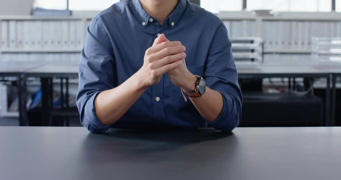Close up of people talking to the camera, businessman in blue shirt sitting at desk with hands clasp