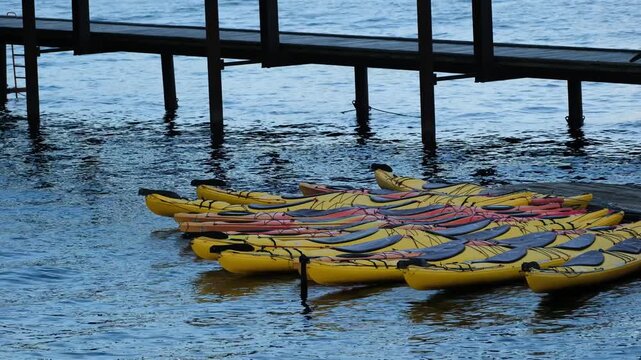 View of yellow kayaks moored at a wooden pier on the water in Copenhagen, Denmark.