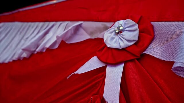 Elegant red and white fabric drapes with pleated folds and a decorative rosette pin ornament, creating a festive national celebration background.