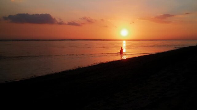 View of a silhouette of a person riding a horse in the ocean during a vibrant sunset at ARYA Sumba in Kodi, East Nusa Tenggara, Indonesia.