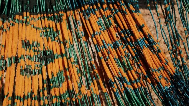 View of traditional ikat weaving threads with vibrant orange and green patterns in Waingapu, Nusa Tenggara Timur, Indonesia.