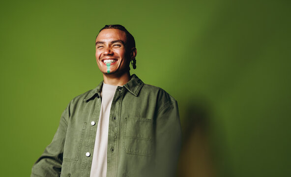 Portrait of a smiling man in green jacket smiling in studio against a green background