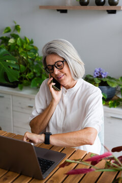Mature white woman multitasking with phone and laptop