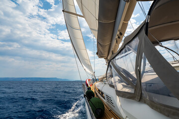 Fototapeta premium Dynamic view from deck of sailing yacht heeling under wind power while cutting through Adriatic waters. White wake, filled sails, a sense of speed, freedom and offshore adventure