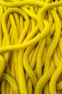 Coiled bright yellow marine rope texture in close up. Nautical safety equipment and durable braided cord background.
