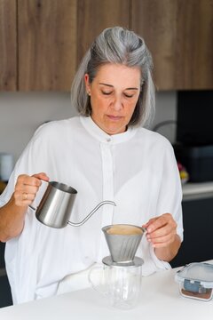 White Woman making drip coffee in kitchen with stainless steel kettle