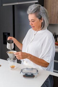 White Woman making pour over coffee in modern home kitchen