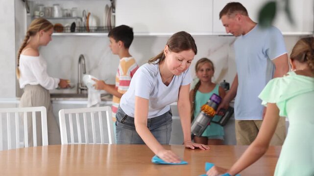 Big tight-knit friendly family cleaning up their bright kitchen 