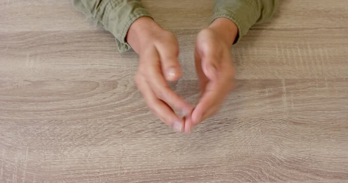 Close up of people talking to the camera, hands clasped together on wooden table, person wearing gre