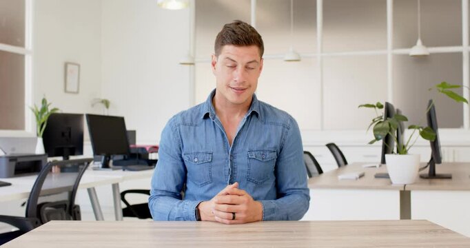 Close up of people talking to the camera, man in denim shirt sitting at desk in office, pointing to