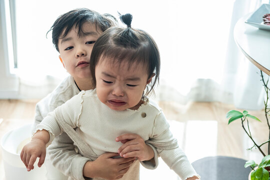 Kind Asian Boy Hugging and Comforting Crying Little Sister at Home
