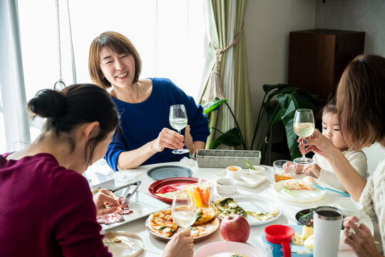 Asian Friends and Toddler Enjoying Home Party Conversation around Dining Table