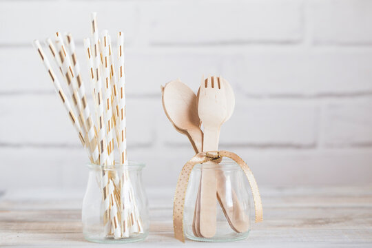 Close-up of Paper drinking straws and wooden cutlery in glass jars on a kitchen worktop