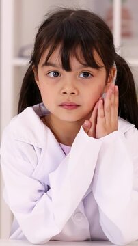 Young Girl in Lab Coat Thinking in Science Classroom