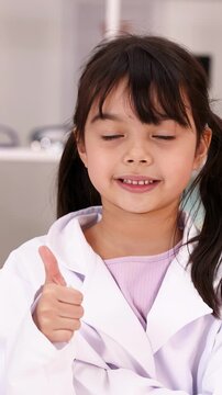 Young Girl in Lab Coat Giving Thumbs Up in Classroom