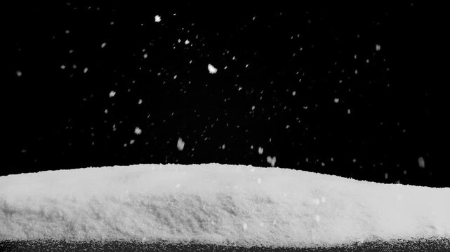 Snow falls on a wooden floor with a pile of snow