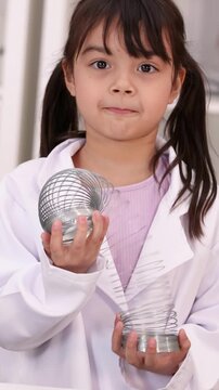 Young Girl in Lab Coat Playing with Metal Spring Toy