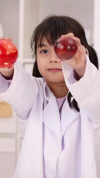 Young Girl in Lab Coat Holding Red Apples in Science Classroom