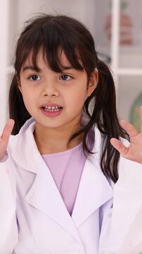 Young Asian Girl in Lab Coat Talking and Gesturing in Classroom