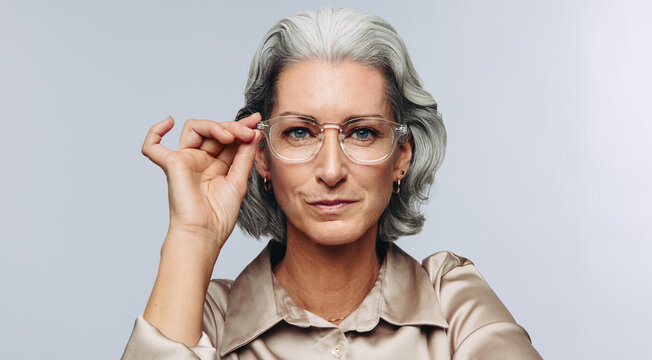 Woman adjusting glasses while posing in studio