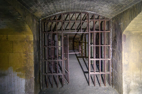 Iron barred gate opening into the vaulted corridor of an abandoned prison