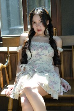 Young woman sitting on wooden bench by window in natural light