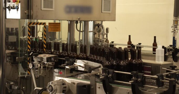 Unfinished beer bottles entering bottling machine in brewery Berlin