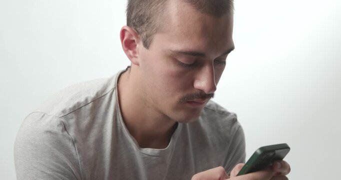 Close-up of Young Man Focused and Typing on Smartphone in Studio