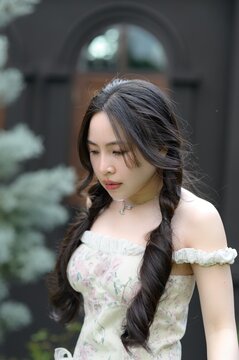 Young woman with long braided dark hair in floral off-shoulder dress outdoors