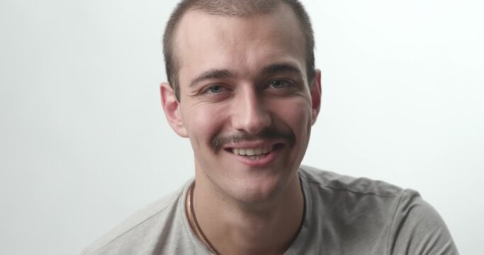 Close-up of Young Man Turning Serious Face into Smile on White Background