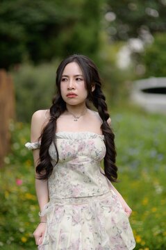 Young Woman Standing in Calm Garden with Flowers and Greenery