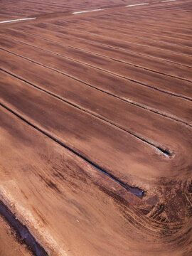 Aerial view of an industrial peat extraction area with parallel drainage ditches and harvested soil fields in Laidzes pagasts, Talsu novads, Latvia.