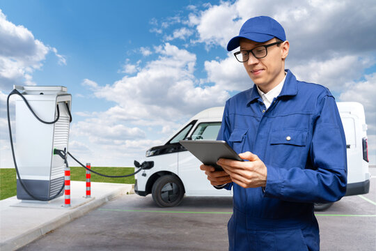 Fleet manager with digital tablet and smartphone next to white electric delivery van