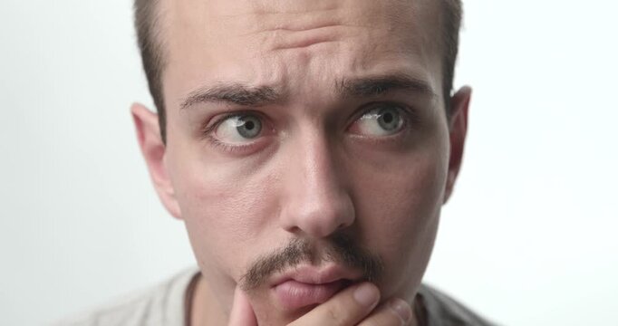 Extreme Close-up of Pensive Young Man Touching Chin and Thinking on White Background