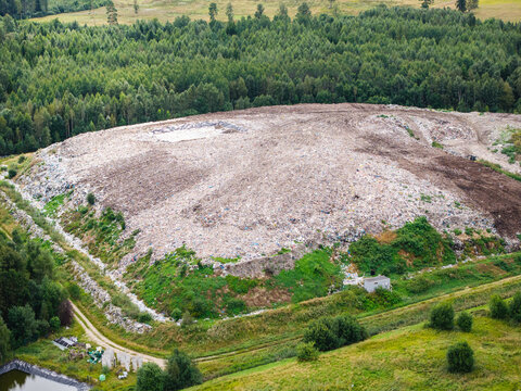 Aerial view of a municipal solid waste landfill surrounded by dense forests and green fields in Laidzes pagasts, Talsu novads, Latvia.