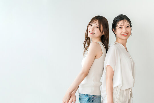 背中合わせで笑顔を見せる仲良しの女性2人