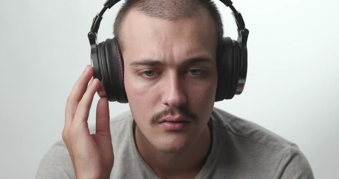 Close-up of Young Man Wearing Headphones Listening to Music and Smiling at Camera