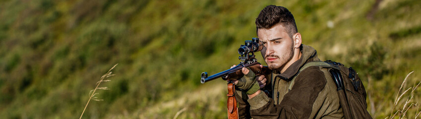 Fototapeta premium Shooter sighting in the target. The man is on the hunt. Hunt hunting rifle. Hunter man. Hunting period. Male with a gun. Close up. Hunter with hunting gun and hunting form to hunt. Hunter is aiming