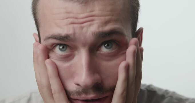 Extreme Close-up of Young Man Showing Anxiety Panic and Fear on White Background