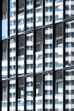 Modern facade with repeated windows and strong vertical lines creating a geometric pattern across dense urban architecture on the exterior of a building