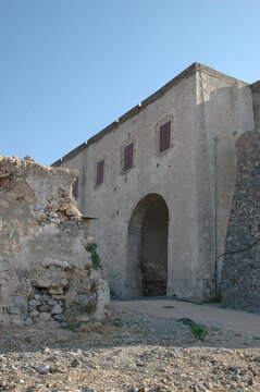 The historic stone building of the venetian palace features a large arched portal and window shutters inside the Fortress of Chora on Kythira island