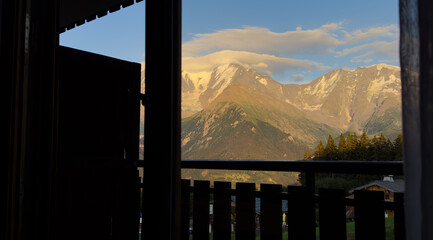 Fototapeta premium Rustic wooden cabin porch with a scenic view of rocky mountains at sunset