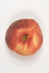 A direct overhead top view of a whole ripe flat peach isolated on a plain white surface © nahhan
