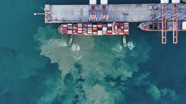 Container ship maneuvering at sea port terminal assisted by tugboats. Heavy cargo vessel docking for freight. Global maritime logistics, international shipping trade, and marine transport.