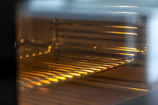 Empty oven interior with metal racks. Warm light inside a kitchen appliance.
